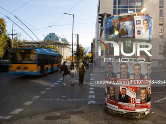 People walk past pre-election posters of parties and coalitions in Sofia, Bulgaria, on October 16, 2024. Bulgaria holds an early parliamenta...