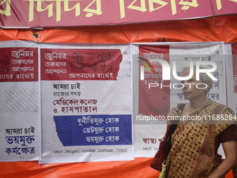 A woman passes next to the banner of junior doctors demanding justice and safety in hospitals at a protest site in Kolkata, India, on Octobe...