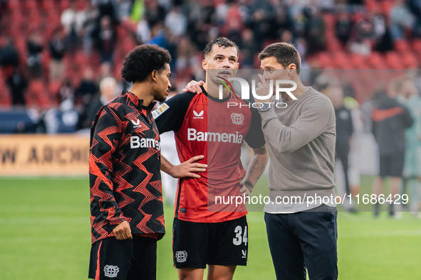 Xabi Alonso, Head Coach of Bayer 04 Leverkusen, speaks with Granit Xhaka and Amine Adli after the Bundesliga match between Bayer 04 Leverkus...