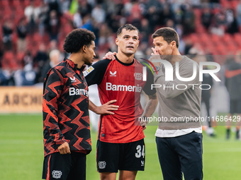 Xabi Alonso, Head Coach of Bayer 04 Leverkusen, speaks with Granit Xhaka and Amine Adli after the Bundesliga match between Bayer 04 Leverkus...