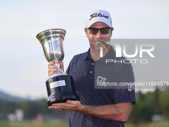 Julien Guerrier of France poses with the trophy on the 18th green following victory in a nine-hole play-off during day four of the Estrella...