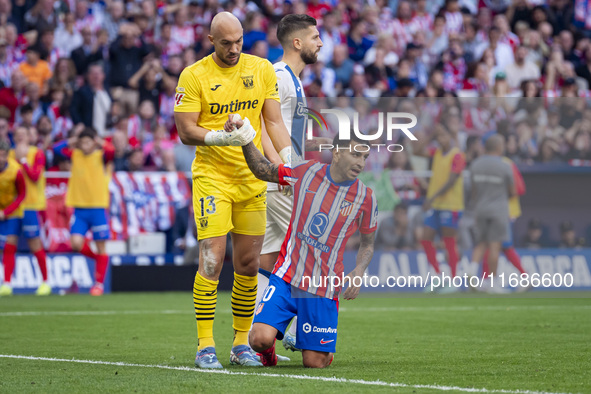 Marko Dmitrovic of CD Leganes (L) helps Angel Correa of Atletico de Madrid (R) during the La Liga EA Sports 2024/25 football match between A...