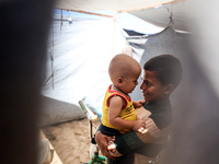 Displaced Palestinian children play outside their tent in a temporary camp in Khan Yunis, Gaza Strip, on October 20, 2024, amid the ongoing...