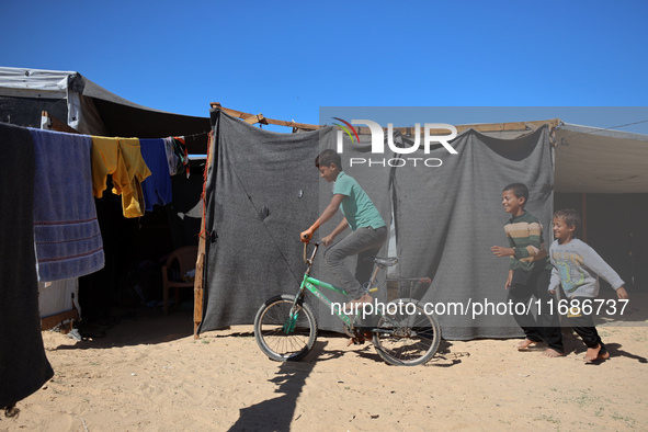 Displaced Palestinian children play outside their tent in a temporary camp in Khan Yunis, Gaza Strip, on October 20, 2024, amid the ongoing...