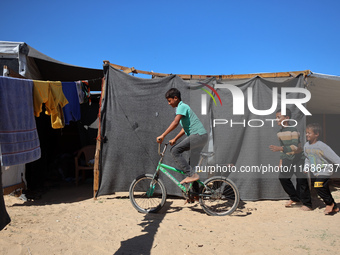 Displaced Palestinian children play outside their tent in a temporary camp in Khan Yunis, Gaza Strip, on October 20, 2024, amid the ongoing...