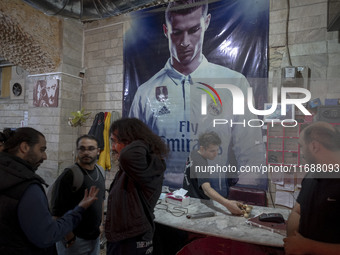 Iranian youths stand together under a poster featuring a portrait of Portuguese soccer player, Cristiano Ronaldo, at a gaming venue at night...