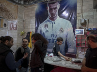 Iranian youths stand together under a poster featuring a portrait of Portuguese soccer player, Cristiano Ronaldo, at a gaming venue at night...