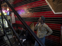 A young Iranian man smokes a cigarette while standing next to his friends at a gaming venue at night in Tabriz, Iran, on October 18, 2024, a...