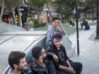 A group of young men sits together on a sidewalk in the historical city of Tabriz, Iran, on October 17, 2024, amid global concerns about war...