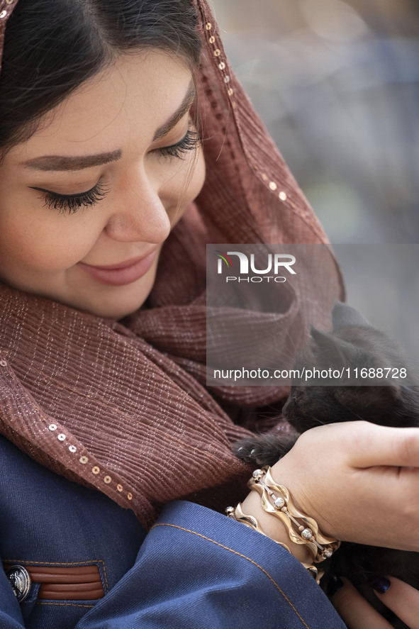 A young Iranian woman hugs a cat while sitting at a historical bazaar in Tabriz, Iran, on October 17, 2024, amid global concerns about war b...