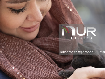 A young Iranian woman hugs a cat while sitting at a historical bazaar in Tabriz, Iran, on October 17, 2024, amid global concerns about war b...