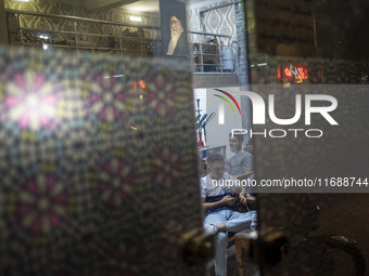 An Iranian man smokes a hookah while sitting under a portrait of Iran's Supreme Leader, Ayatollah Ali Khamenei, at a traditional teahouse at...