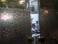 An Iranian man smokes a hookah while sitting under a portrait of Iran's Supreme Leader, Ayatollah Ali Khamenei, at a traditional teahouse at...