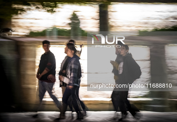 A group of Iranian youths walks together along a sidewalk at night in the historical city of Tabriz, Iran, on October 17, 2024, amid global...