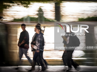 A group of Iranian youths walks together along a sidewalk at night in the historical city of Tabriz, Iran, on October 17, 2024, amid global...