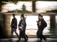 A group of Iranian youths walks together along a sidewalk at night in the historical city of Tabriz, Iran, on October 17, 2024, amid global...