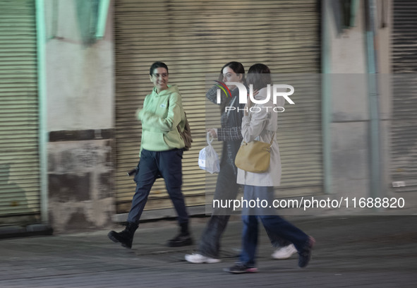 Young Iranian women walk together along a sidewalk at night in Tabriz, Iran, on October 18, 2024, amid global concerns about war between Ira...