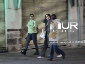 Young Iranian women walk together along a sidewalk at night in Tabriz, Iran, on October 18, 2024, amid global concerns about war between Ira...