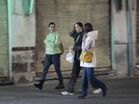 Young Iranian women walk together along a sidewalk at night in Tabriz, Iran, on October 18, 2024, amid global concerns about war between Ira...