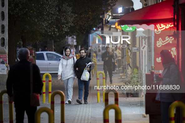 A young Iranian couple walks along a street at night in the historical city of Tabriz, Iran, on October 17, 2024, amid global concerns about...