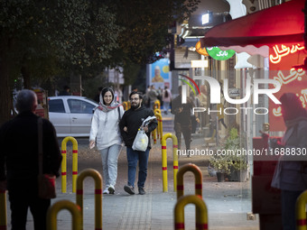 A young Iranian couple walks along a street at night in the historical city of Tabriz, Iran, on October 17, 2024, amid global concerns about...