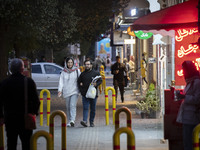 A young Iranian couple walks along a street at night in the historical city of Tabriz, Iran, on October 17, 2024, amid global concerns about...