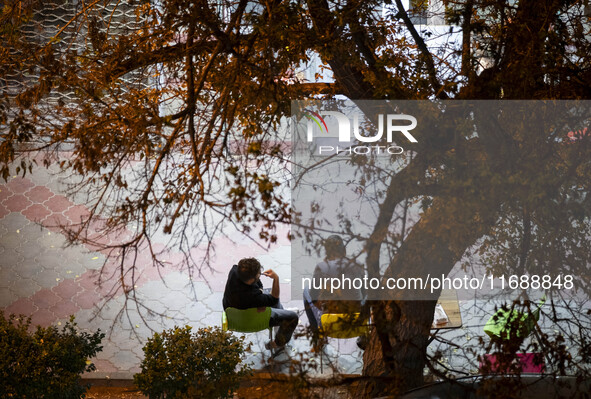 Two Iranian men sit together on a sidewalk at night in the historical city of Tabriz, Iran, on October 16, 2024, amid global concerns about...