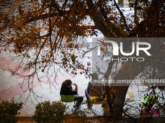 Two Iranian men sit together on a sidewalk at night in the historical city of Tabriz, Iran, on October 16, 2024, amid global concerns about...