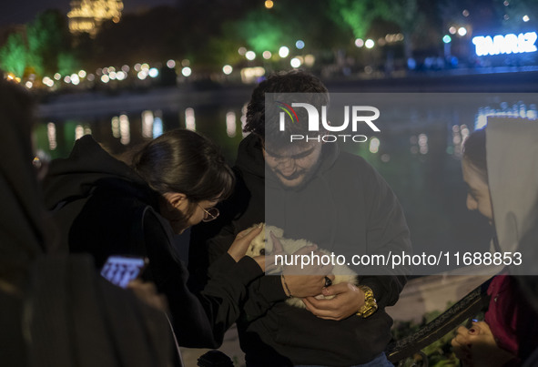 Iranian youths stand together while one of them holds a pet at a historical site at night in Tabriz, Iran, on October 17, 2024, amid global...