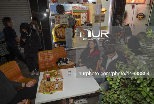 Turkish youths are at an outdoor fast-food restaurant at night in the historical city of Tabriz, Iran, located 624 km (388 miles) northwest...