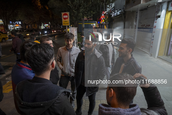 Iranian youths stand together on a sidewalk at night in Tabriz, Iran, on October 18, 2024, amid global concerns about war between Iran and I...