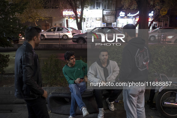 Young Iranian men gather on a sidewalk at night in Tabriz, Iran, on October 18, 2024, amid global concerns about war between Iran and Israel...