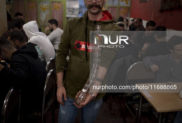 A young Iranian man works at his cafe and poses for a photograph while holding cups in the historical city of Tabriz, Iran, on October 18, 2...