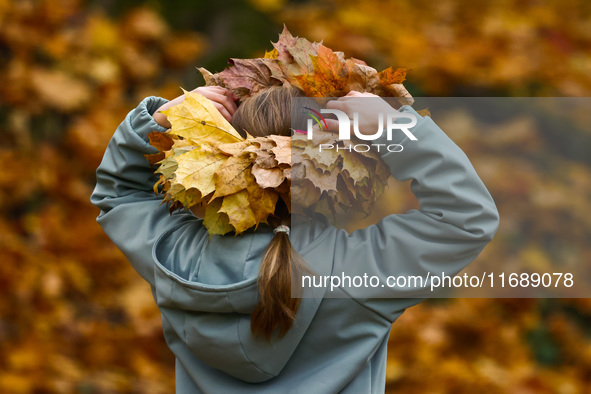 A girls wears a wreath of leaves on a sunny autumn day at Bednarski Park in Krakow, Poland on October 20th, 2024. 