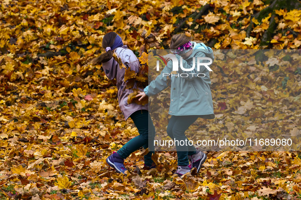 Children play throwing leaves on an autumn day at Bednarski Park n Krakow, Poland on October 20th, 2024. 