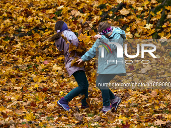 Children play throwing leaves on an autumn day at Bednarski Park n Krakow, Poland on October 20th, 2024. (