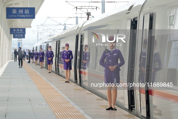 A crew member welcomes passengers to board the first train of the Weifang-Yantai High-Speed Railway at Laizhou Station in Yantai, China, on...