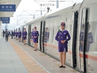 A crew member welcomes passengers to board the first train of the Weifang-Yantai High-Speed Railway at Laizhou Station in Yantai, China, on...