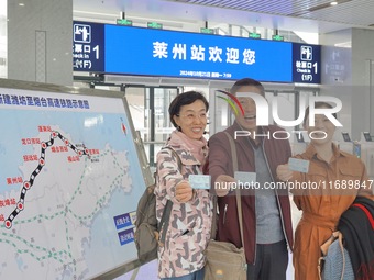 Passengers take the first train of the Weifang High-Speed Railway and pose for a group photo at Laizhou Railway Station in Yantai, China, on...