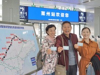 Passengers take the first train of the Weifang High-Speed Railway and pose for a group photo at Laizhou Railway Station in Yantai, China, on...