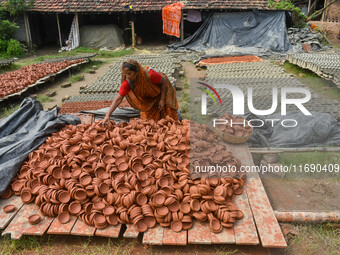 A lady dries clay pots, which are made for sale ahead of the Diwali festival celebration in Kolkata, India, on October 21, 2024. (