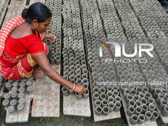 A lady dries clay pots, which are made for sale ahead of the Diwali festival celebration in Kolkata, India, on October 21, 2024. (