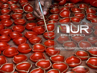 Workers apply final touches to clay oil lamps, which are made for sale ahead of the Diwali festival celebration in Kolkata, India, on Octobe...