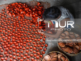 Workers apply final touches to clay oil lamps, which are made for sale ahead of the Diwali festival celebration in Kolkata, India, on Octobe...