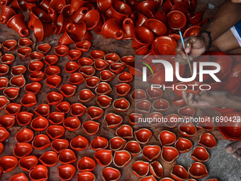 Workers apply final touches to clay oil lamps, which are made for sale ahead of the Diwali festival celebration in Kolkata, India, on Octobe...