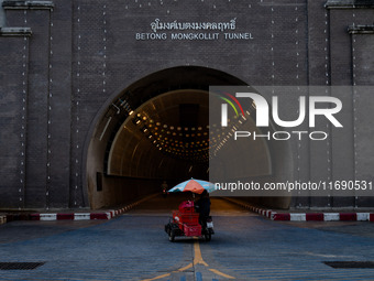 A seller with a colorful umbrella motorcycle cart enters Betong Mongkollit Tunnel in Betong, Yala Province, Thailand, on October 21, 2024. (