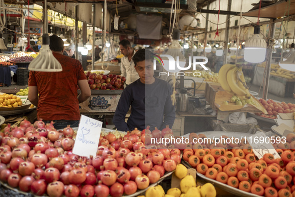 A young Iranian salesman stands at a fruit stand at a bazaar in the historical city of Tabriz, Iran, on October 17, 2024. 