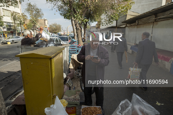 An Iranian vendor checks a card reader while standing outside a bazaar in the historical city of Tabriz, located 624 km (388 miles) northwes...