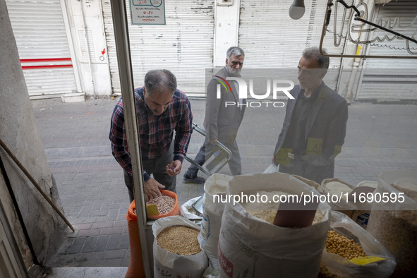 An Iranian shopkeeper checks legumes placed outside his shop at a bazaar in the historical city of Tabriz, Iran, on October 17, 2024. 