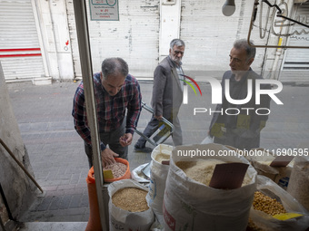 An Iranian shopkeeper checks legumes placed outside his shop at a bazaar in the historical city of Tabriz, Iran, on October 17, 2024. (